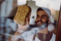 Huishoudhulp Germani maakt de ramen proper in de woonkamer