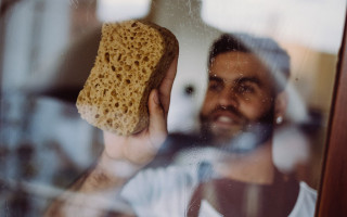 Mannelijke huishoudhulp gaat met spons over ramen
